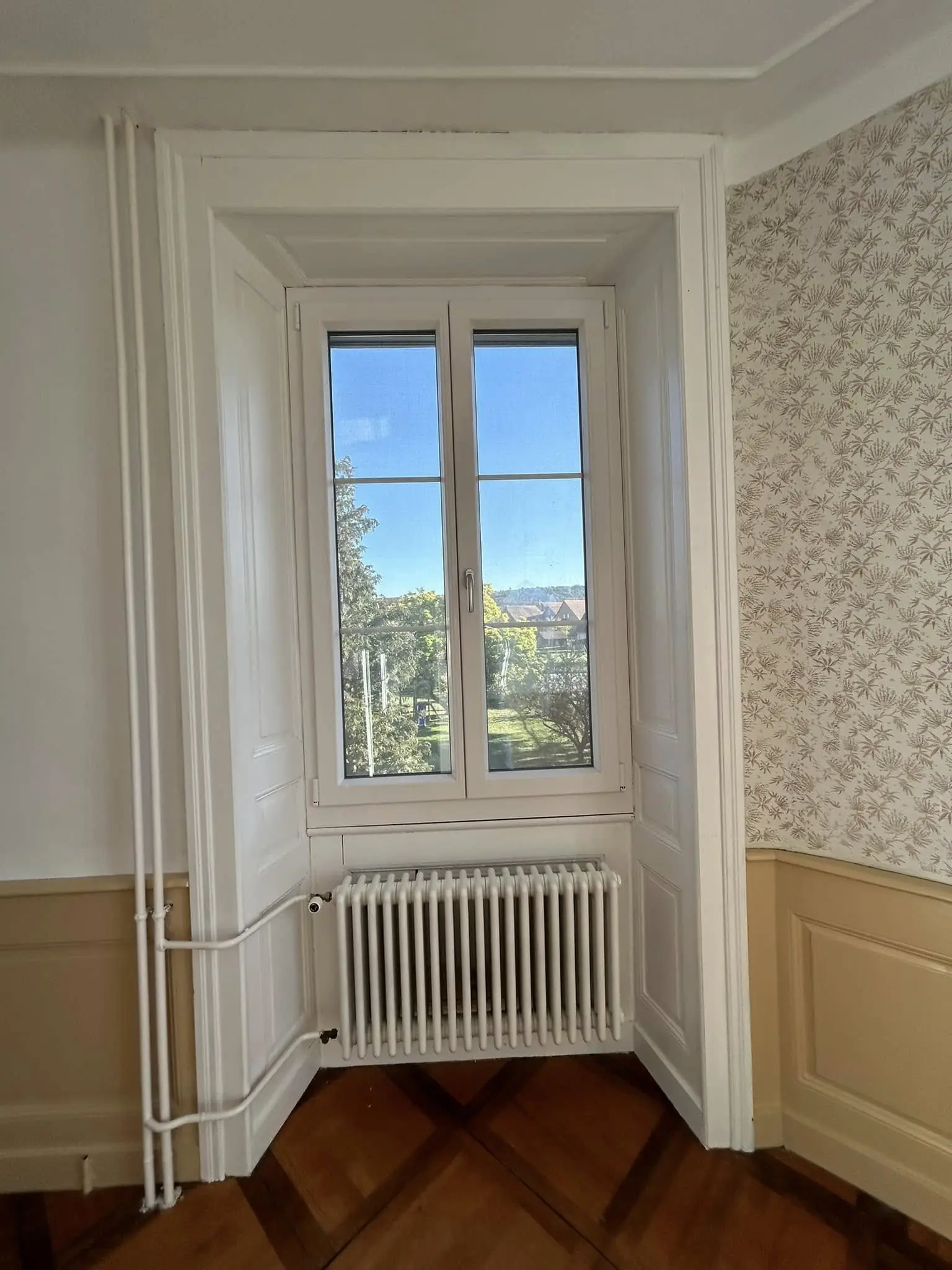 Embrasure de fenêtre repeinte à côté d'un papier peint conservé