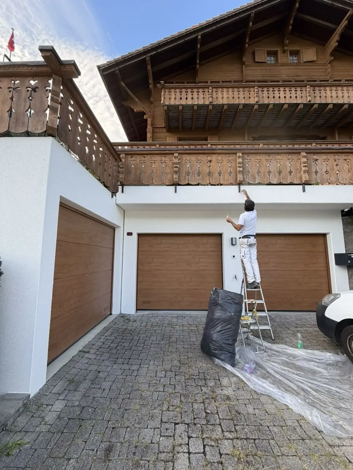 Peintre sur une échelle devant les boiseries au-dessus du garage