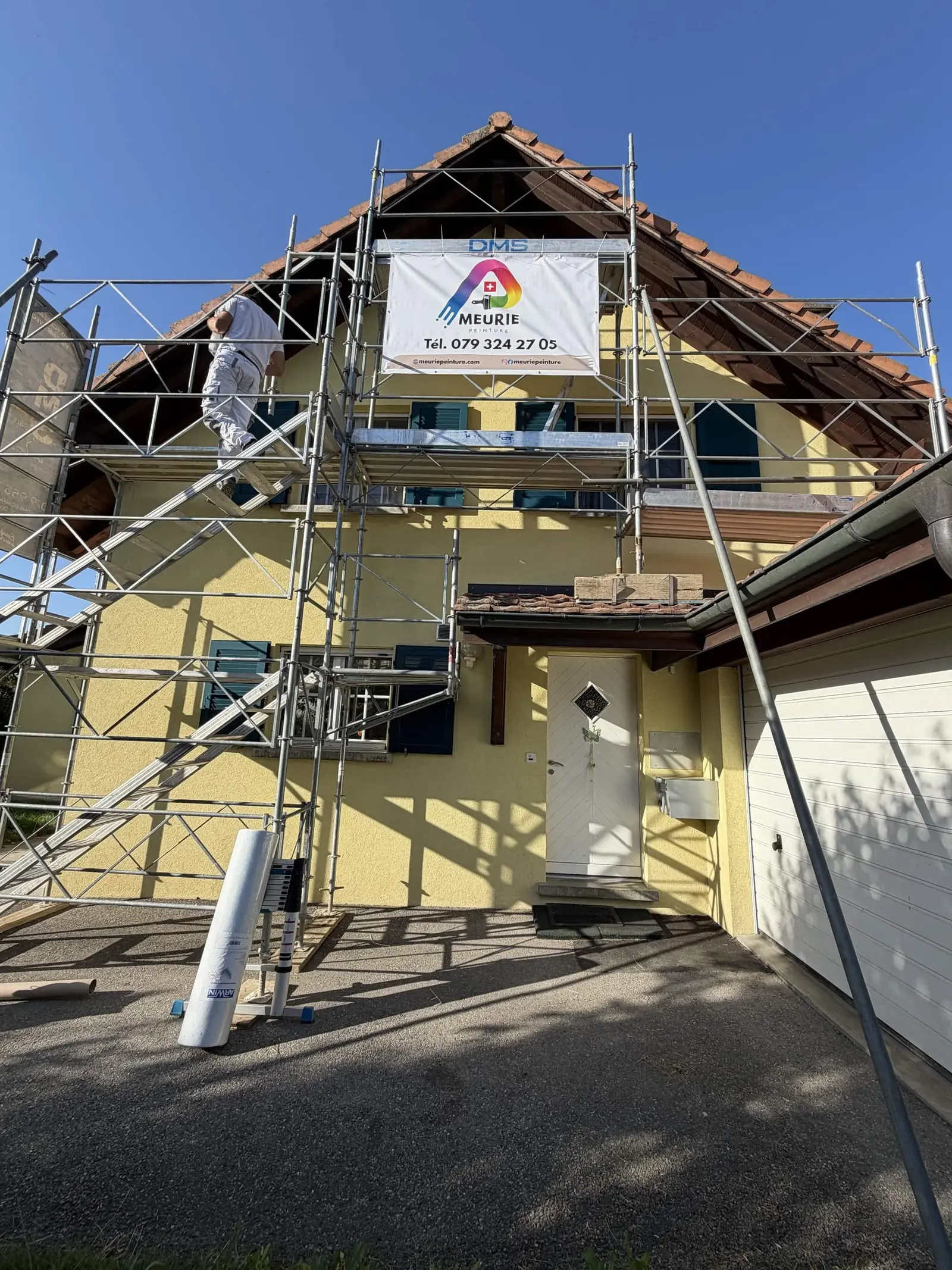 Façade jaune en cours de reprise, échafaudage monté jusqu'au faîte