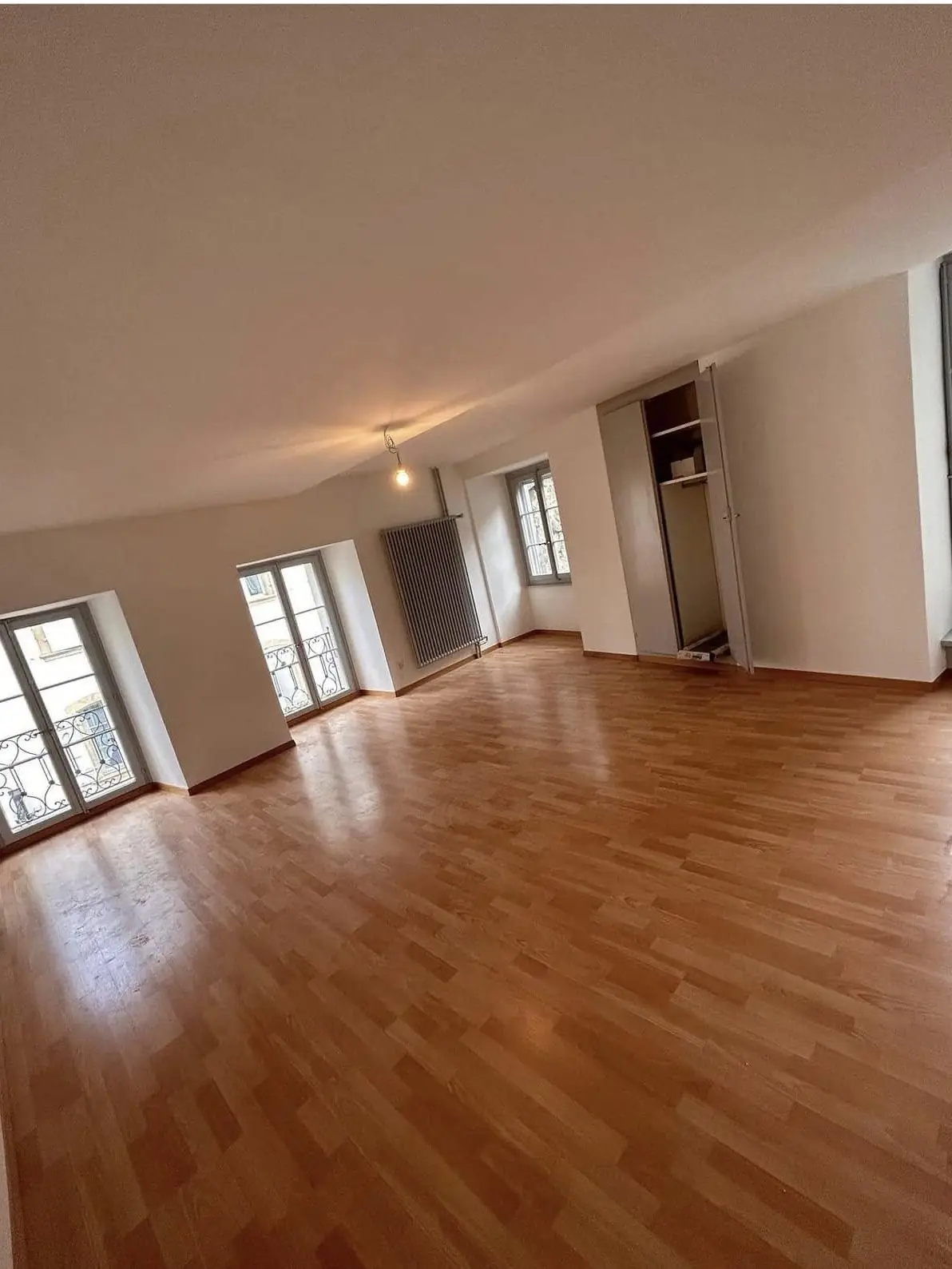 Grand séjour vide, murs blancs et parquet remis en état