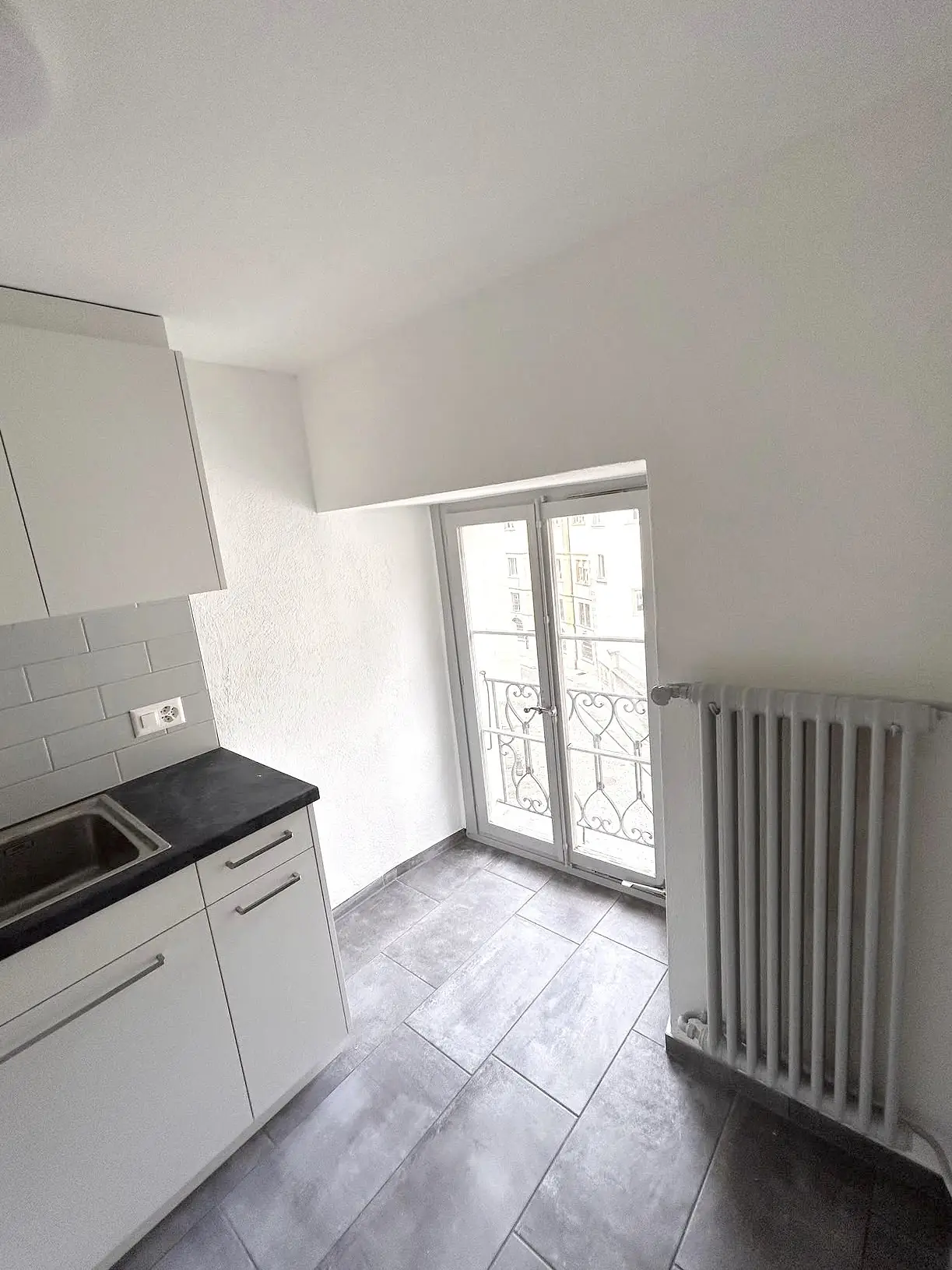 Cuisine repeinte en blanc avec radiateur à colonnes sous la fenêtre