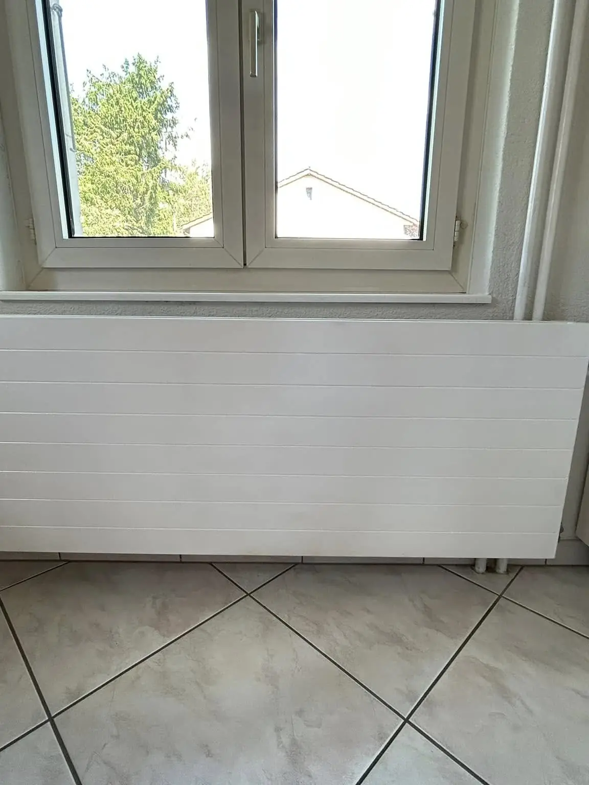 Radiateur plat repeint sous une fenêtre en sous-pente